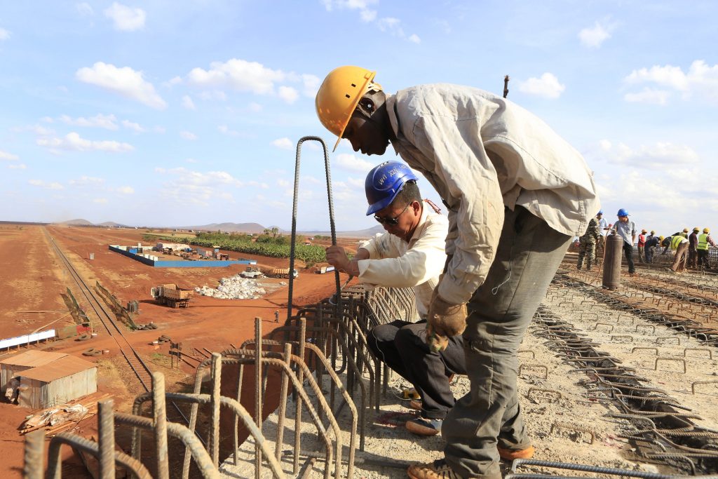 A Chinese engineer and a local construction worker work on a section of the Mombasa-Nairobi standard gauge railway (SGR) in Emali, Kenya October 10, 2015. The China Road and Bridge Corporation (CRBC) tasked with the construction work at a cost of 3.8 billion U.S. dollars is due for completion in mid-2017. REUTERS/Noor Khamis  - D1AERZDORFAA